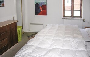 Ein Schlafzimmer mit Bett, Kommode, Heizkörper und Fenster.