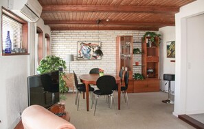 A dining area with a brick wall, wooden ceiling, and a dining table with chairs. - Cozy home in Rudkøbing with WiFi (Rudkøbing)