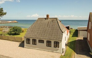 Ein Küstenhaus mit Ziegeldach, Schornstein und Blick auf das Meer.