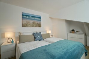 Ein Schlafzimmer mit einem Bett, zwei Nachttischen, einem Wandbild und einem kleinen Schrank.