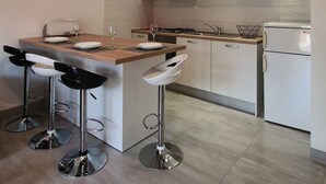 A modern kitchen with white cabinets, a wooden countertop, and stainless steel bar stools. - Holiday apartment mit Terrasse (Šilo)