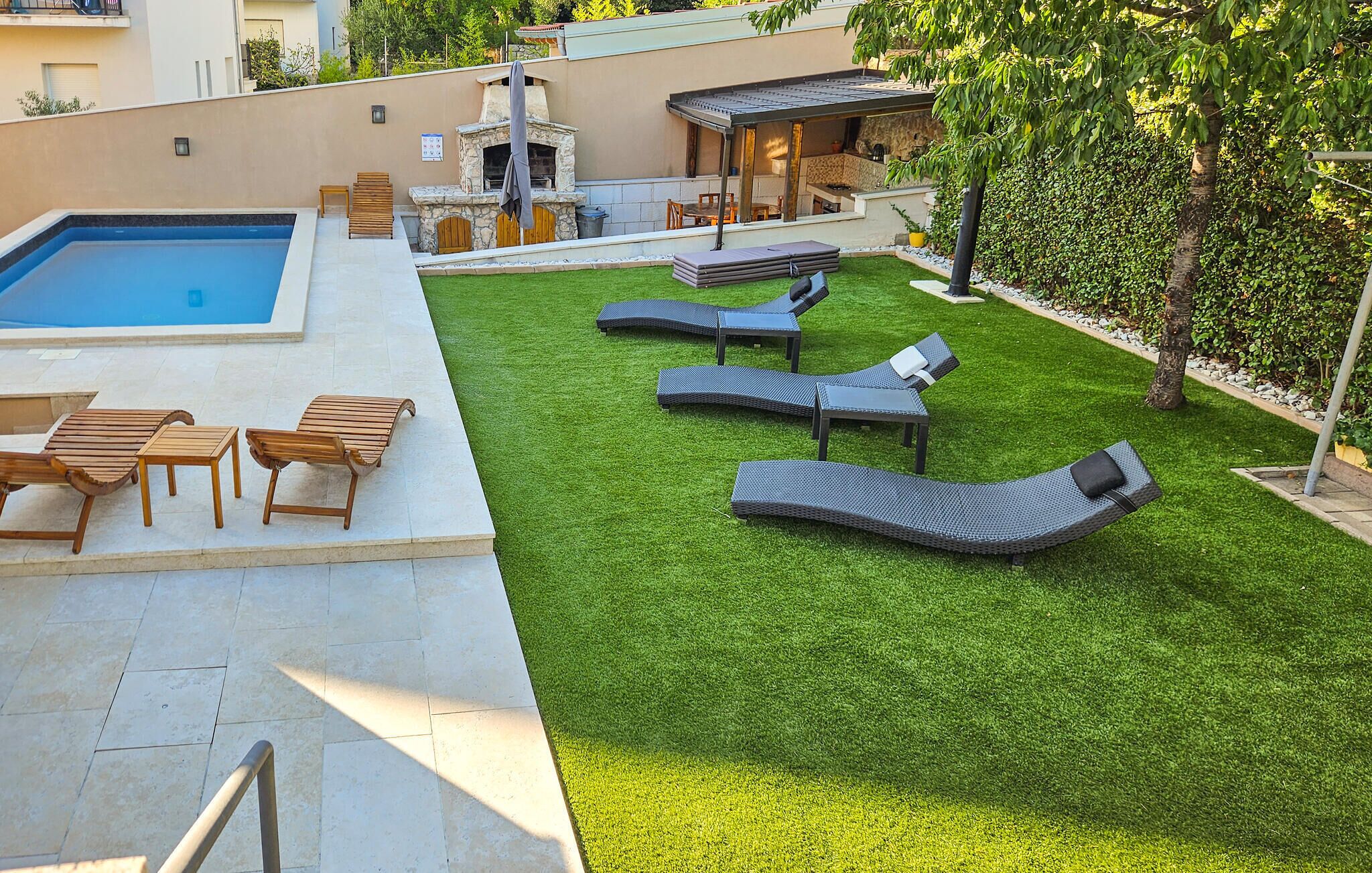 A pool area with lounge chairs and a barbecue setup.