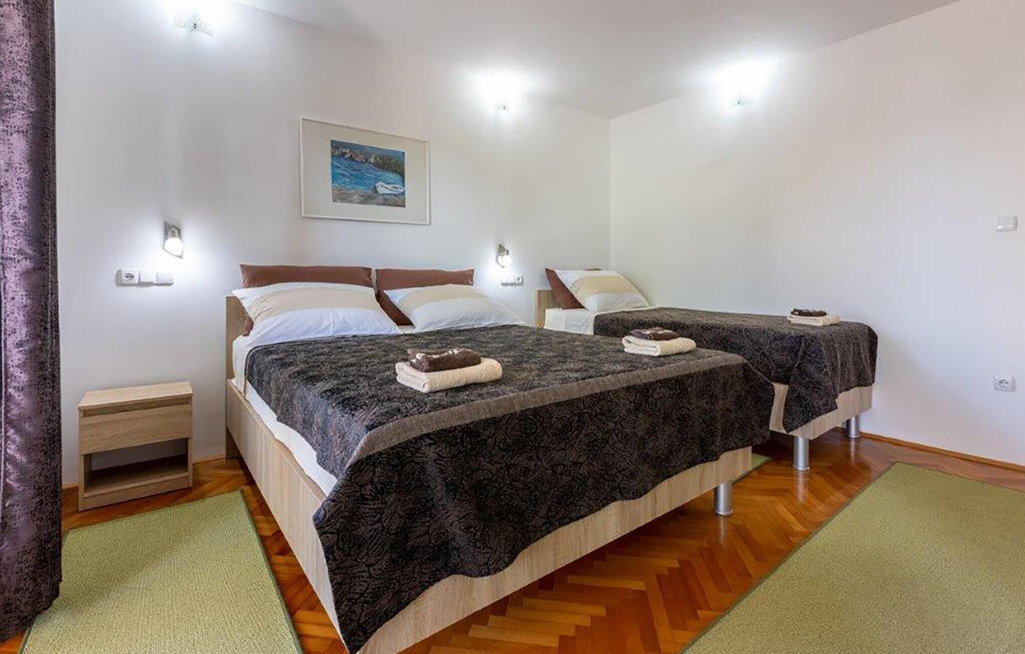 A double room with two beds, a wooden floor, and a painting on the wall.