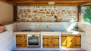 Eine Steinsäule mit Fliesenrückwand, Holzschränken und einem eingebauten Backofen.