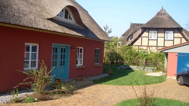 A traditional house with a thatched roof, a red exterior, and a paved garden area. - Landschek, Holiday home Das Ulmenhaus - Holiday home (Rankwitz)