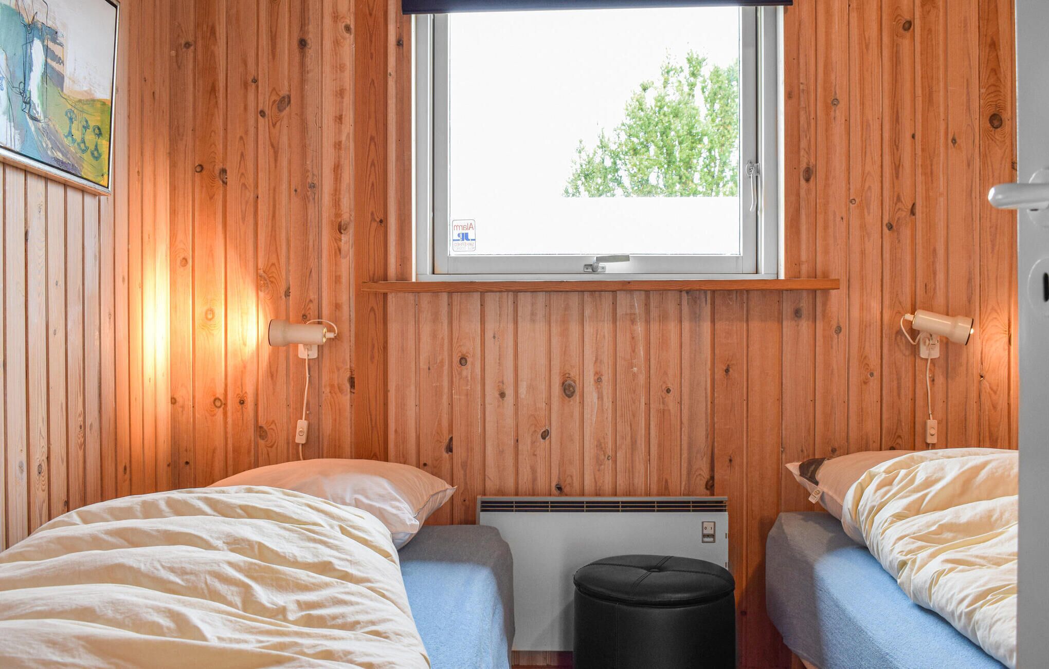 Una baita con due letti, una finestra, un termosifone e pareti in legno.