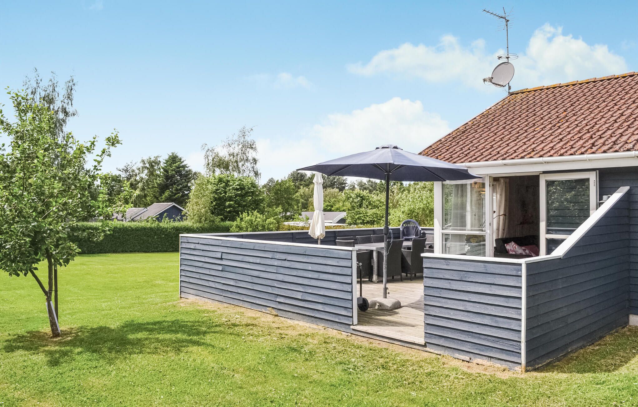 A covered outdoor area with a table and chairs, a grill, and a large umbrella.
