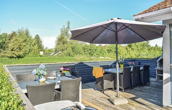 An outdoor patio with wicker furniture, a table, and an umbrella.
