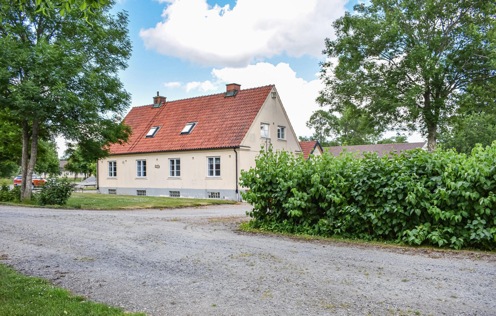 A two-story building with a red-tiled roof, multiple windows, and a gravel driveway.