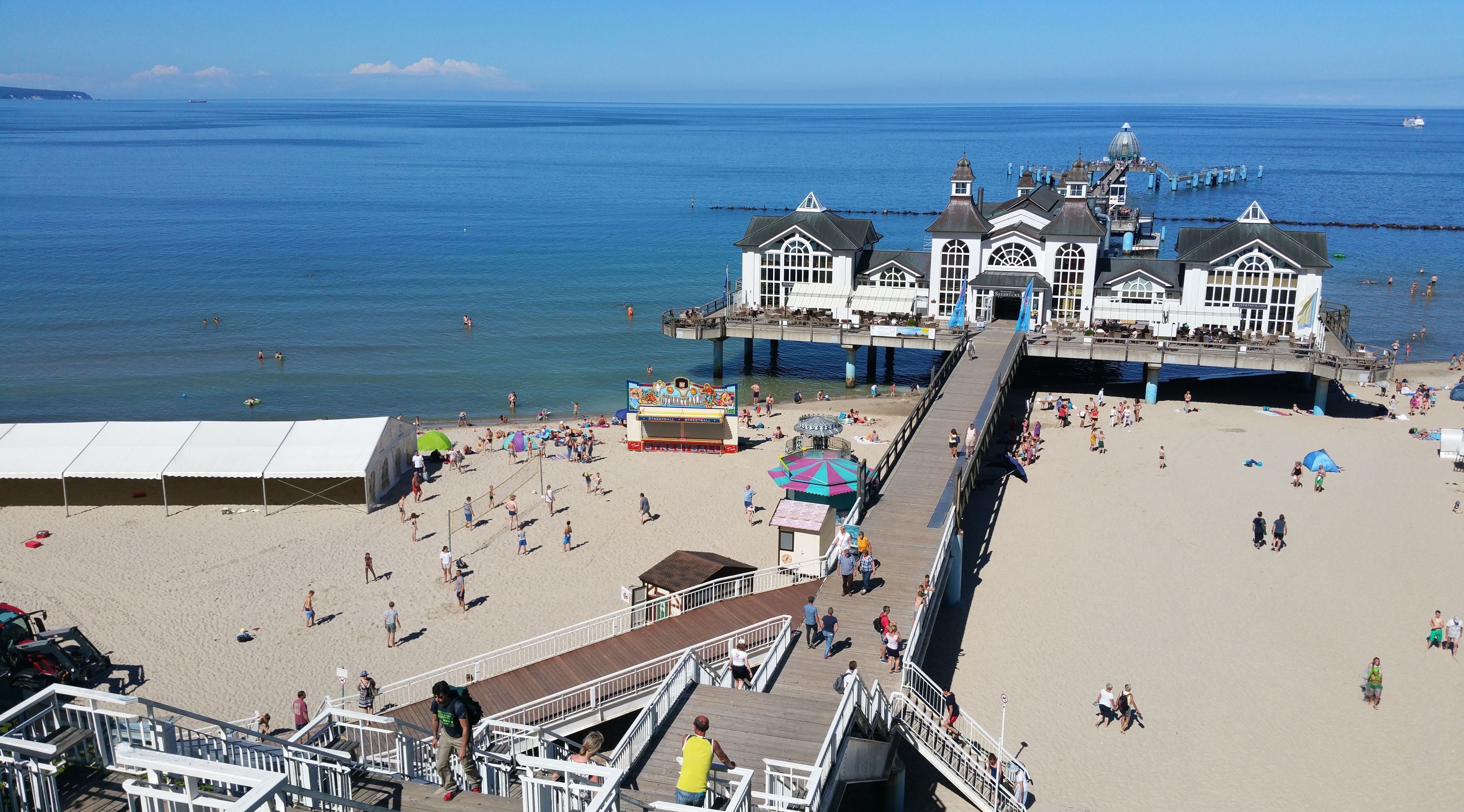 Una spiaggia con un molo, un grande edificio con molte finestre e una vista libera sull'oceano.