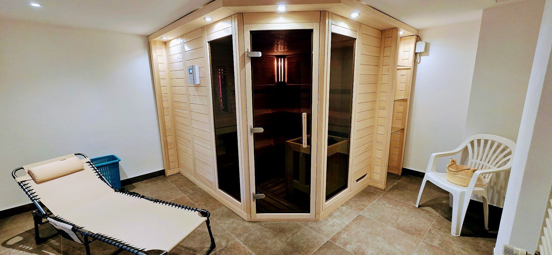 A corner room with a sliding door, a chair, a small table, and a wall-mounted light fixture.