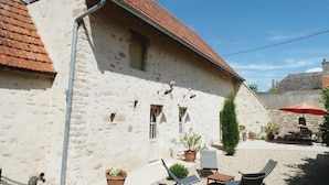 A building with a tiled roof, stone walls, and a small patio area with outdoor seating and potted plants. - Stunning home in RUFFEY LES BEAUNE (RUFFEY LES BEAUNE)