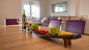 Ein Esstisch mit Obst- und Käseplatte, Weingläsern und einer Flasche.
