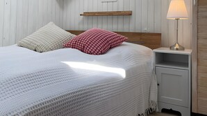 A neatly arranged bedroom with a skylight, a bedside table with a lamp, and a wooden headboard.