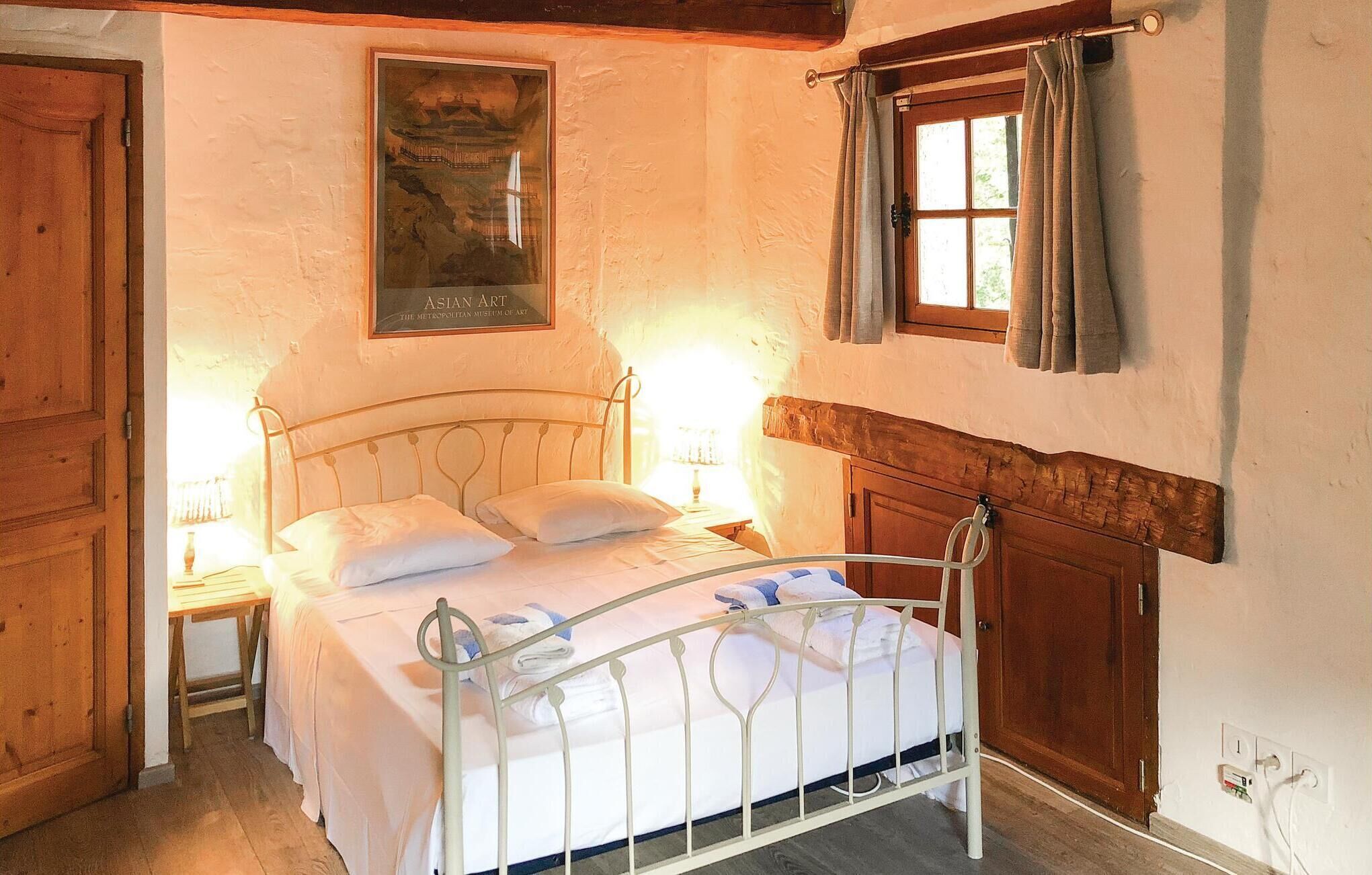 A bedroom with a metal bed frame, a wooden door, a window with curtains, and a poster on the wall.