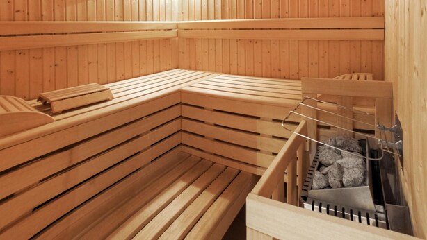 Un sauna avec des bancs en bois et un banc muni d’une serviette.
