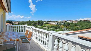 Varanda com mesa e cadeiras, com vista para uma cidade e vegetação.
