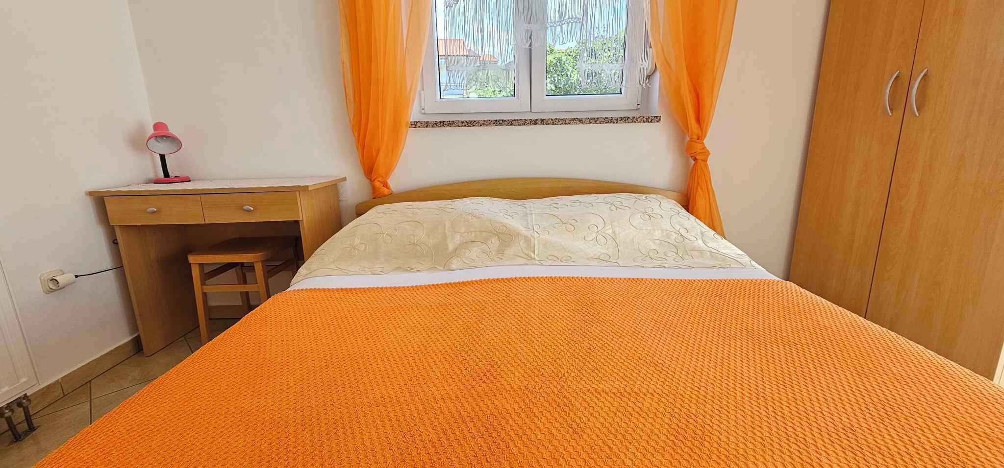 A bedroom with a bed, a desk, and a wardrobe.