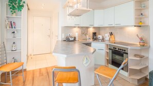 Una cucina moderna con mobili bianchi, un'isola centrale con sgabelli, un forno integrato e una lampada a sospensione.