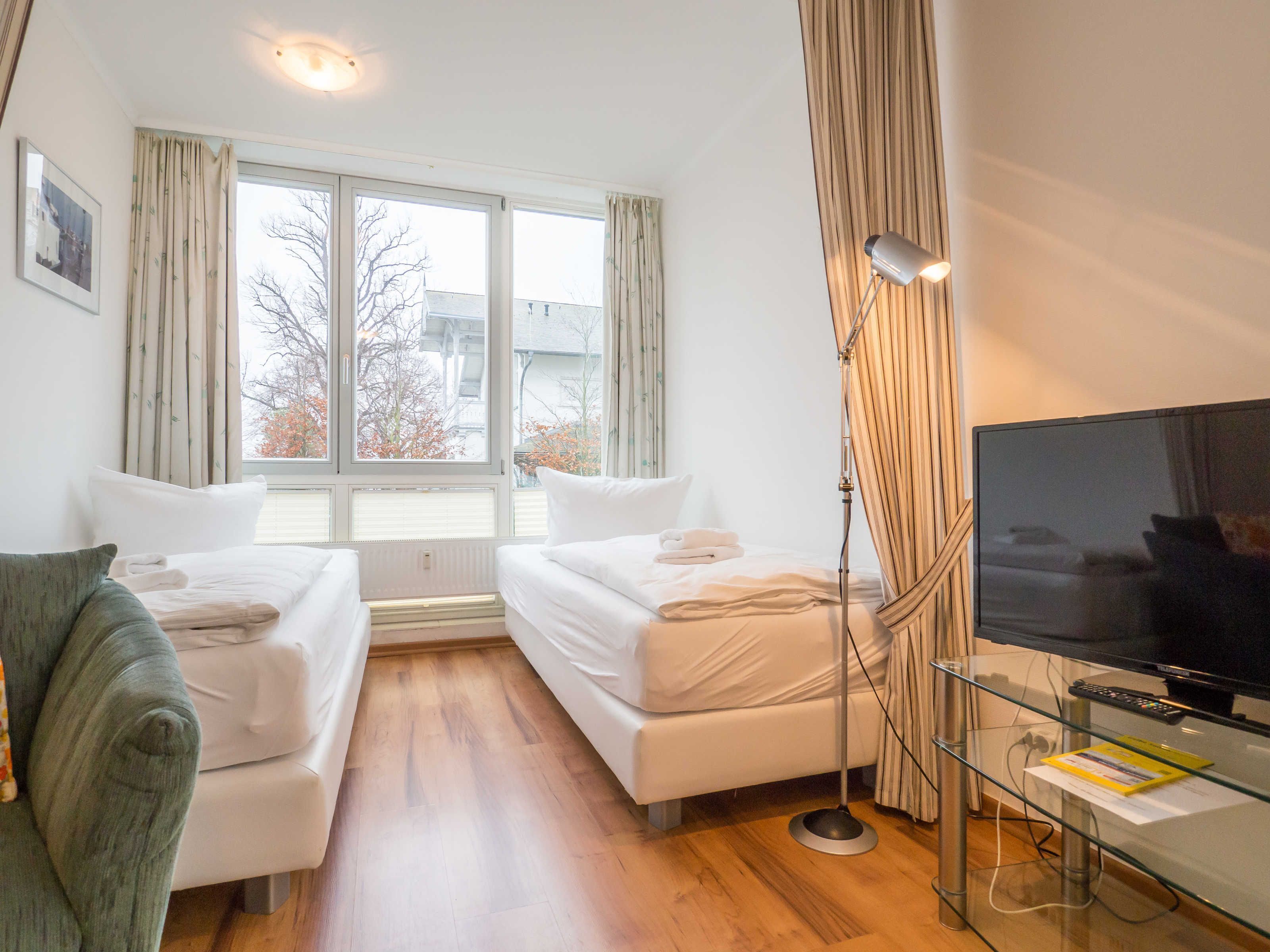 A hotel room with two beds, a TV, and a desk with a lamp.