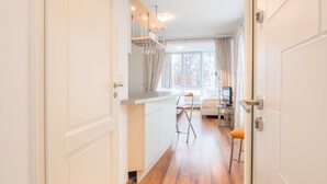 Una cucina moderna con un piano di lavoro in legno, un'area pranzo con un tavolo e sedie bianche, e un'ampia finestra con tende.