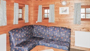 Ett hörnrum med en blå soffa med mönster, träväggar, ett träbord och en klocka på väggen.