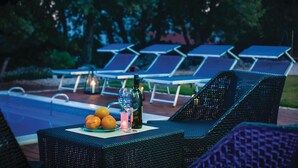 Buitenloungestoelen, een zwembad en een tafel met fruit en drankjes.