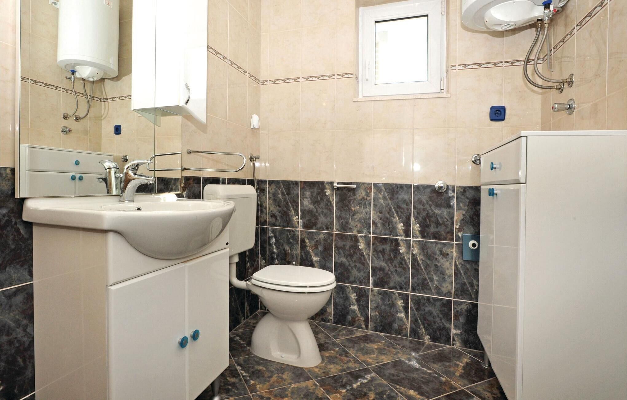 Ein Badezimmer mit weißem Waschbecken, WC und Duschbereich.