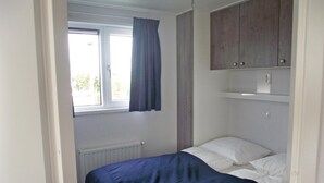 A small, single-bed room with a window, a radiator, and a wooden wardrobe. - Awesome home in Breukelen (Breukelen)