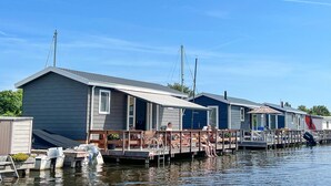 A row of mobile homes with docked boats, each with a small deck and outdoor seating. - Awesome home in Breukelen (Breukelen)