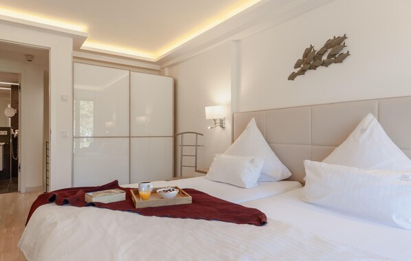 A hotel room with a bed, a bedside table with a tray of breakfast, a wall-mounted lamp, and a door leading to another room. - Lovely apartment in Binz with WiFi (Prora/Rügen)