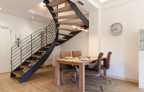 A modern kitchen with a spiral staircase, a dining table with chairs, and a wall clock. - Lovely apartment in Binz with WiFi (Prora/Rügen)