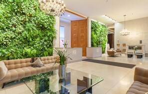A modern lobby with a green wall, a sofa, a glass coffee table, and a reception desk.