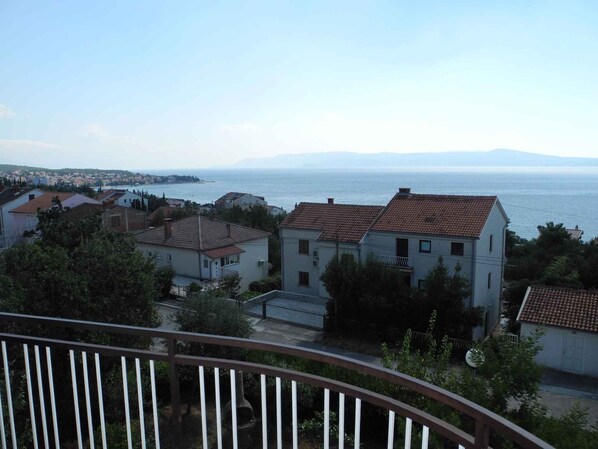 A coastal residential area with houses, a clear view of the sea, and a distant mountain range.