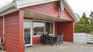 A red wooden building with a covered patio area featuring a table and chairs. - Pet friendly home in Rømø with sauna (Rømø)