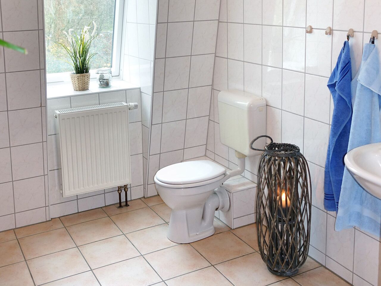 A bathroom with a toilet, a radiator, a sink, and a hanging towel rack.