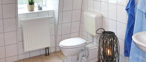 A bathroom with a toilet, a radiator, a sink, and a hanging towel rack.
