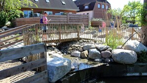 A wooden bridge over a small stream with rocks and a wooden fence. - Intercontinental Family Home - North American Mediterranean Vacation Rentals (Hasselberg)