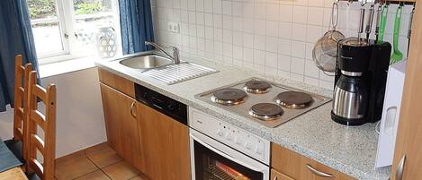 A kitchen with wooden cabinets, a stainless steel sink, a stove, an oven, and a coffee maker.