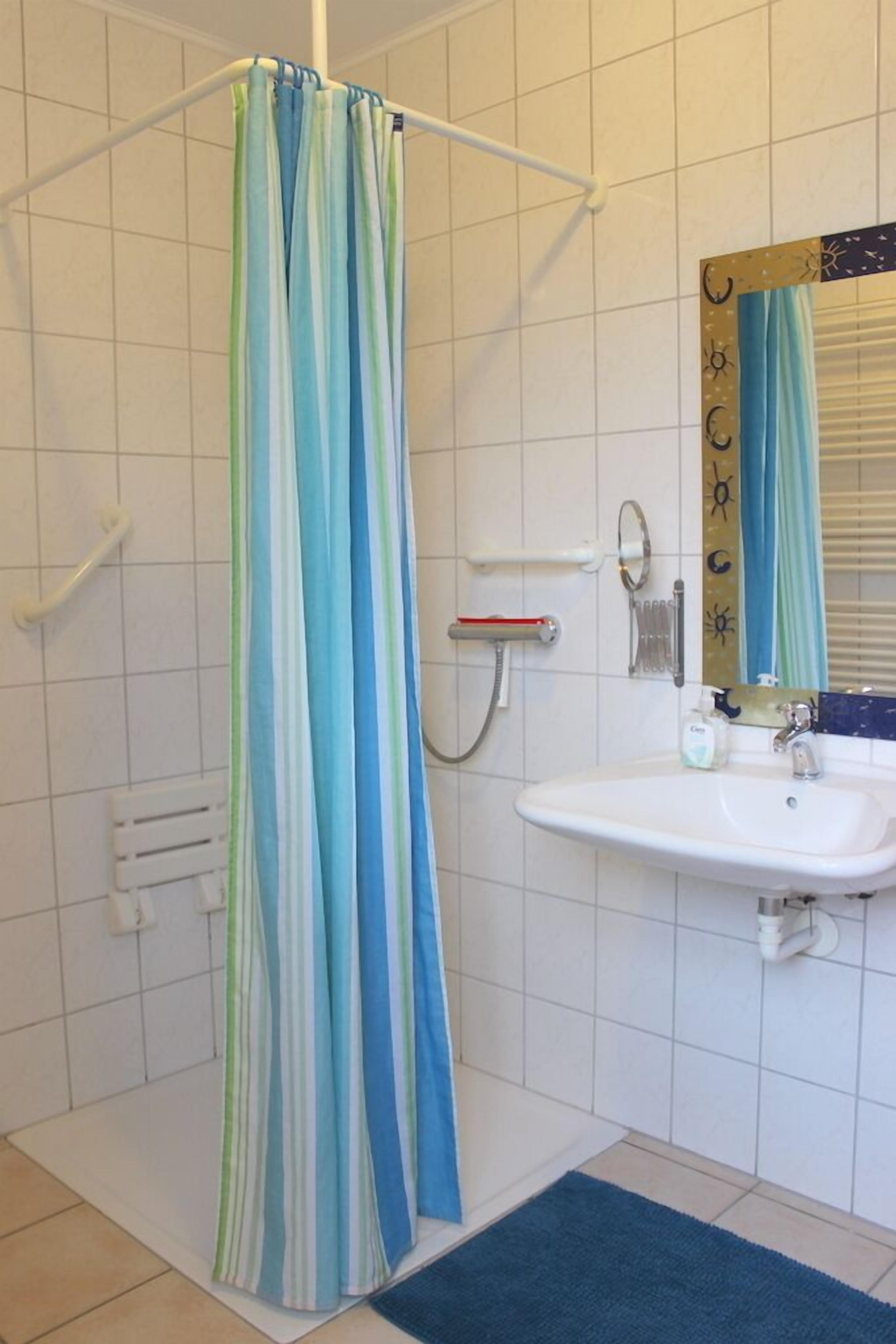 Ein Badezimmer mit Duschvorhang, Waschbecken und Spiegel.
