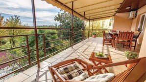 Un espace extérieur abrité, doté d’une table et de chaises, entouré d’une rambarde en métal et agrémenté de plantes en pot.