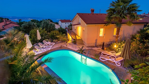 Une piscine avec des chaises longues, un escalier menant à une maison et une vue sur la mer.
