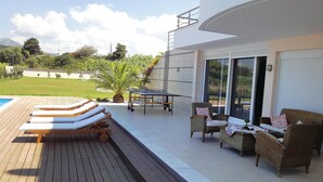 A poolside area with lounge chairs, a table, and wicker furniture.