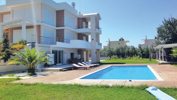 A modern multi-story building with a swimming pool, outdoor seating, and a well-maintained garden.