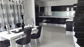 A modern kitchen with black cabinets, a white countertop, and a glass backsplash.