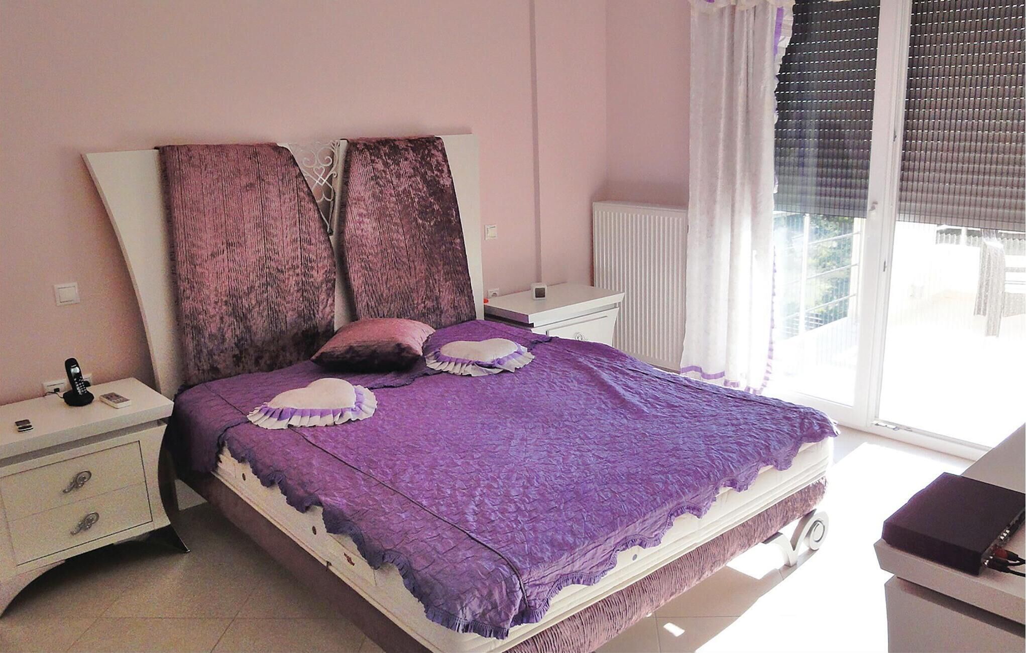Een slaapkamer met een bed, nachtkastjes, een dressoir en een raam met jaloezieën.