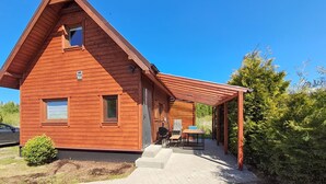 A wooden cabin with a covered porch, a small table, and a grill area. - 2 bedroom lovely home in Podamirowo (Podamirowo)