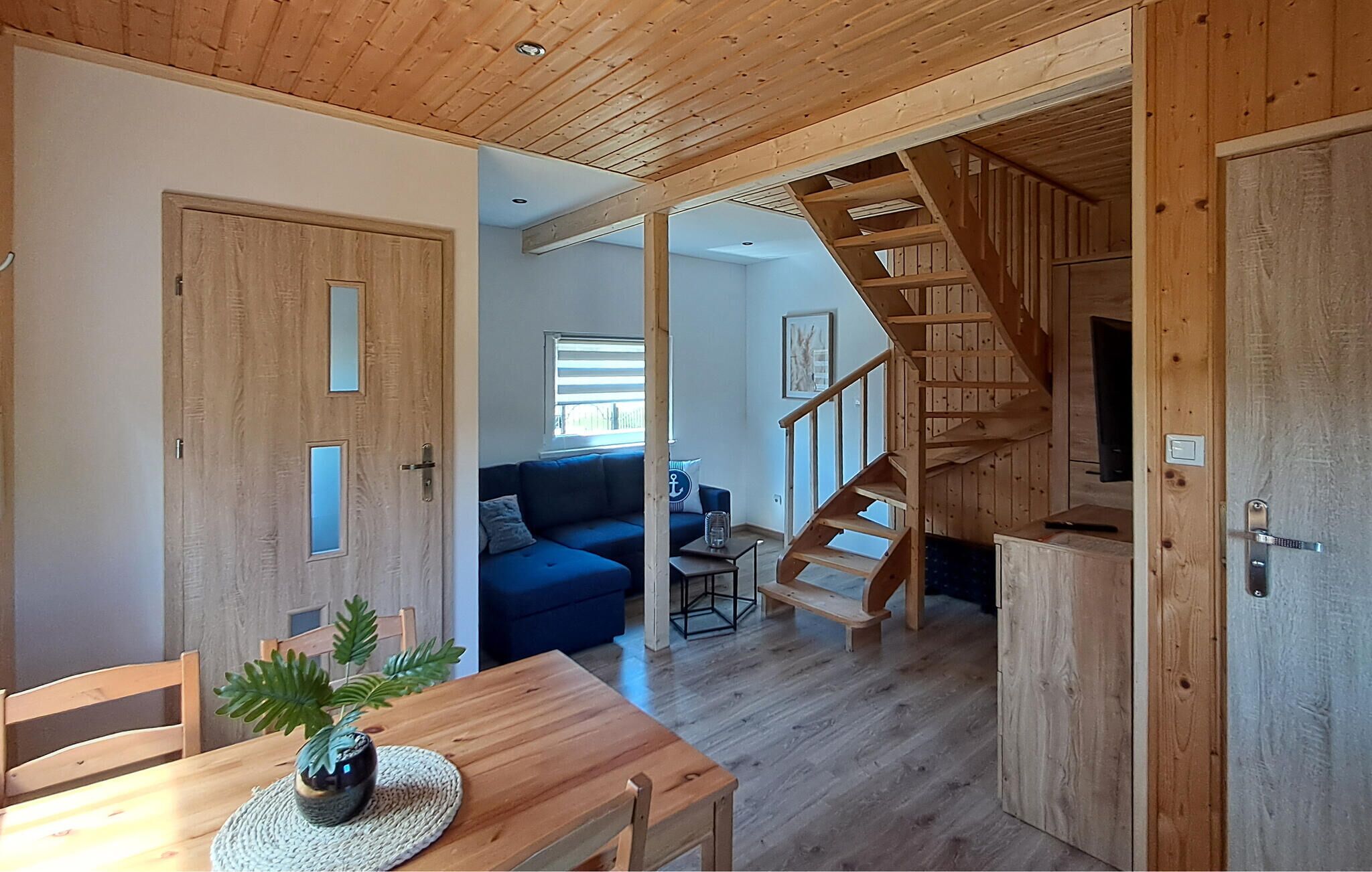 Un interior de madera con una escalera, un sofá y un comedor.