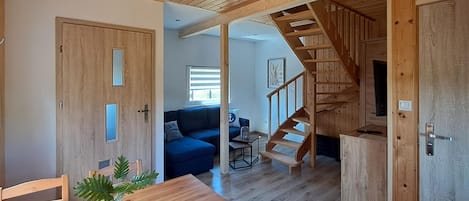 A wooden interior with a staircase, a sofa, and a dining area.