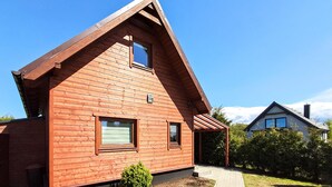 A wooden house with a gabled roof, a small porch, and a paved driveway. - 2 bedroom lovely home in Podamirowo (Podamirowo)